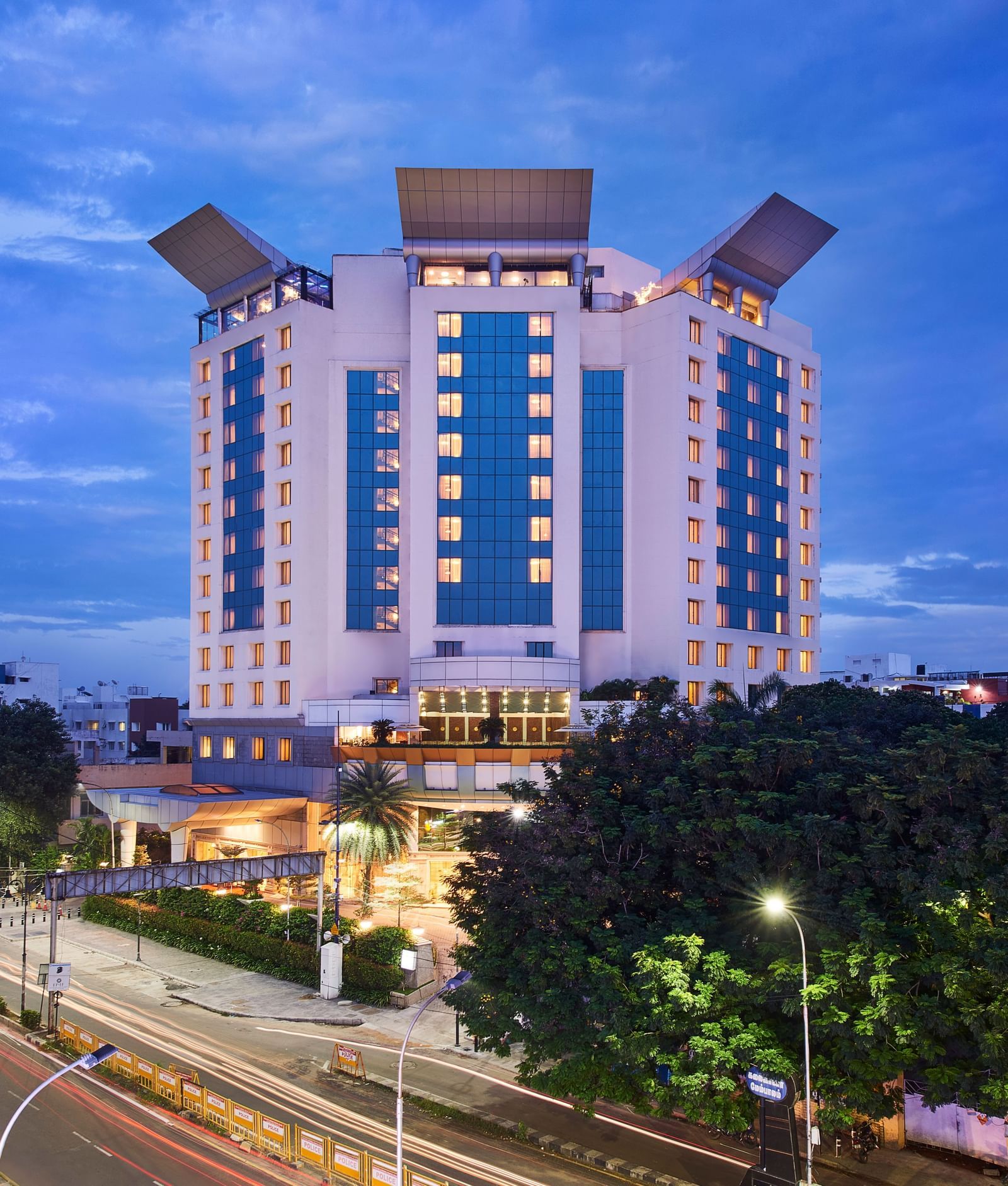 An image of a facade surrounded by trees and in the front yard there are cards parked - Accord Hotels and Resorts